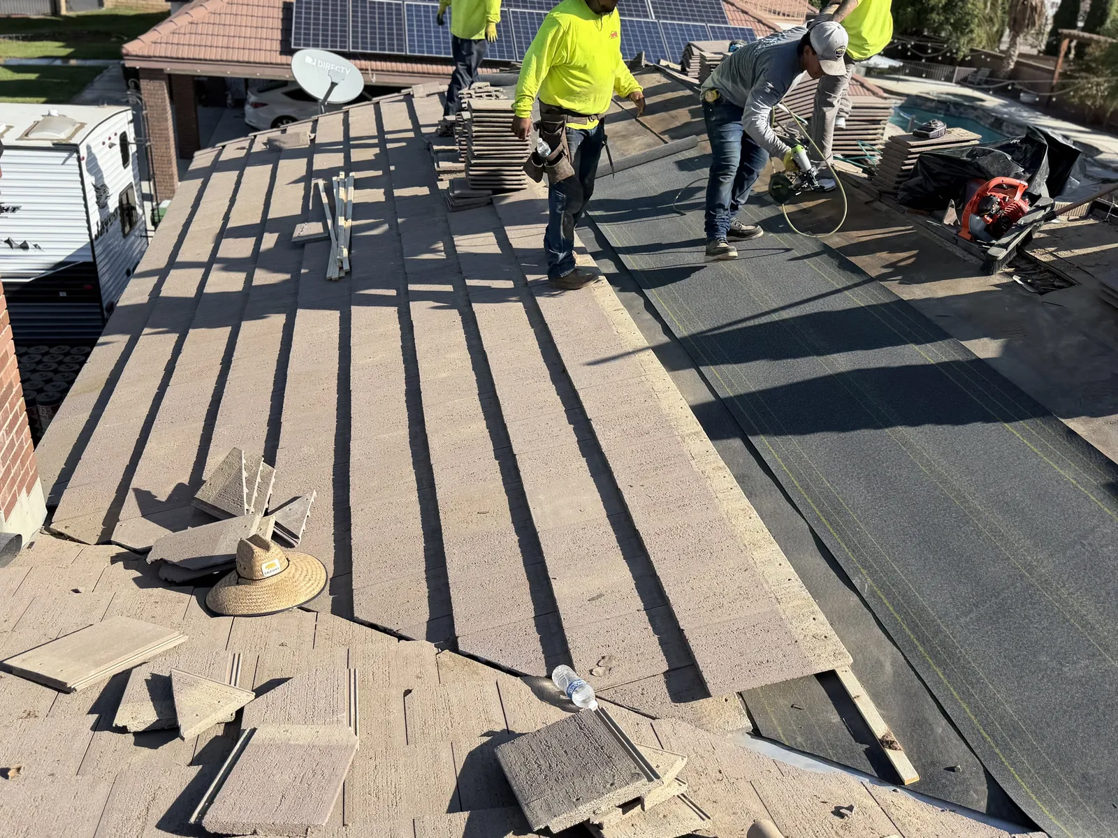Superior crew in hi-vis laying concrete roof tile over new underlayment